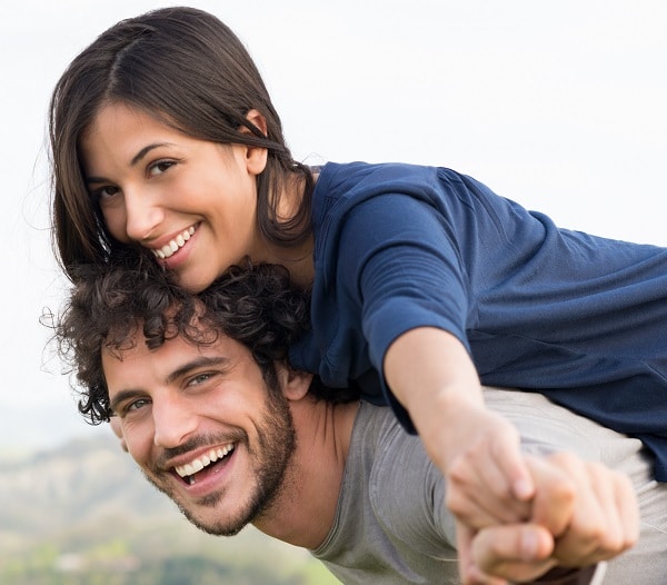 Woman on Man's back smiling at the camera