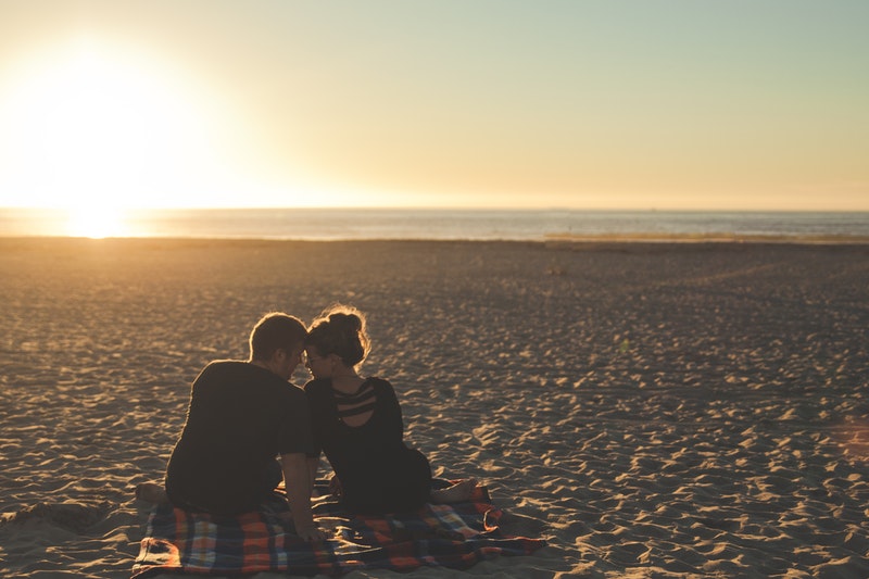 couple sat on beach during sunset